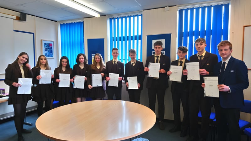 Schüler der Corfe Hills School im Klassenraum mit blauen Jalousien halten ihre Zertifikate.