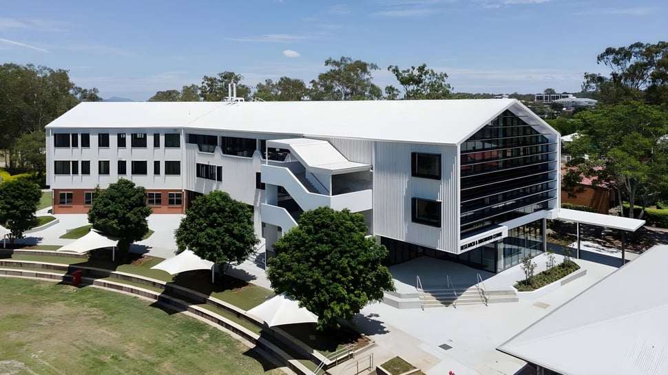 Das moderne mehrstöckige Gebäude der Corinda State High School ist von Bäumen und Grünflächen umgeben.