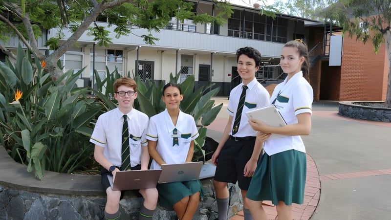 Vier Schüler der Corinda State High School stehen vor dem Schulgebäude umgeben von grüner Vegetation.