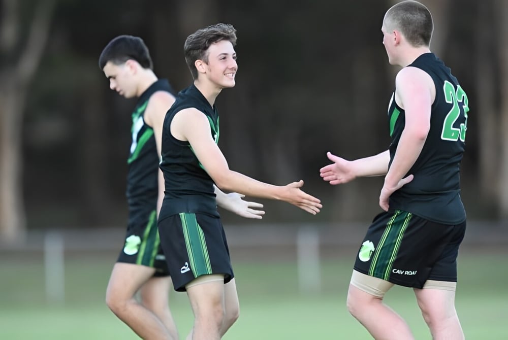 Zwei Schüler der Corinda State High School geben sich auf dem Sportplatz die Hand.