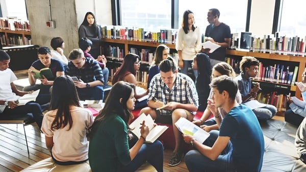 Eine Gruppe Schüler der Cork Educate Together Secondary School diskutiert sitzend auf dem Boden in der Schulbibliothek.