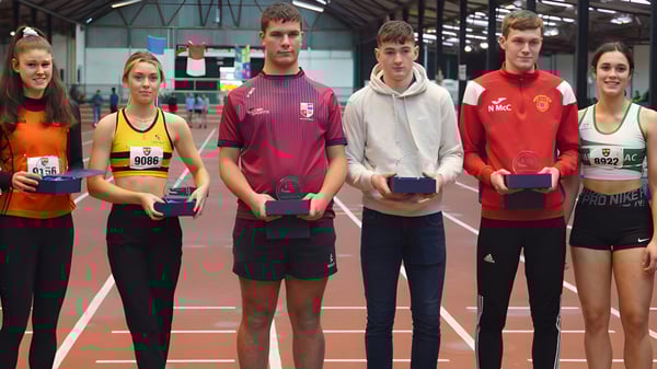 Schüler der Cork Educate Together Secondary School stehen auf einer Hallenbahn und zeigen ihre gewonnenen Pokale und Medaillen.