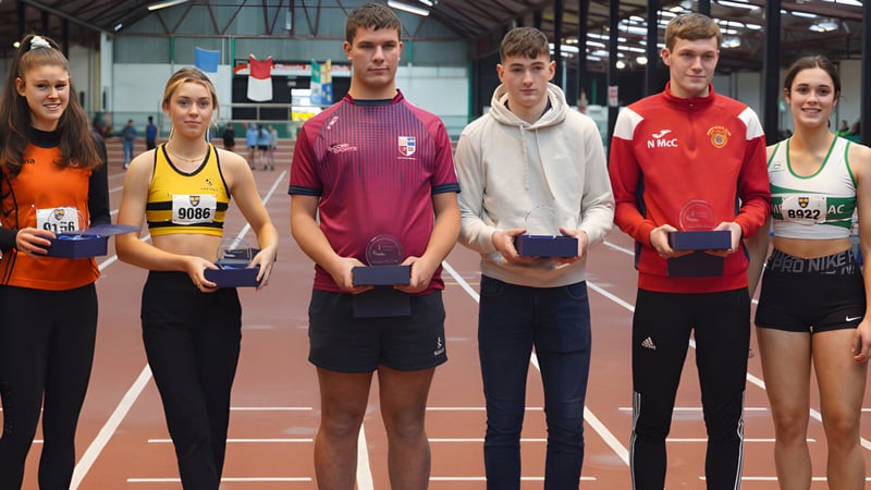 Schüler der Cork Educate Together Secondary School stehen auf einer Hallenbahn und zeigen ihre gewonnenen Pokale und Medaillen.