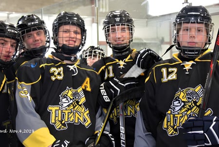 Eine Gruppe junger Hockeyspieler der Corner Brook Regional High School steht in der Umkleidekabine in ihren Trikots und Helmen.