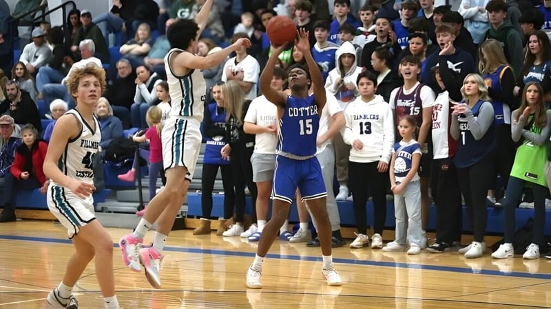 Schüler spielen ein Basketballspiel auf dem Spielfeld der Cotter Schools mit Zuschauern auf den Rängen.