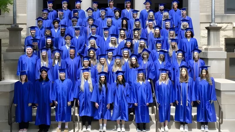 Eine große Gruppe von Absolventinnen und Absolventen der Cotter Schools steht in blauen Talaren und Hüten auf den Stufen eines Gebäudes mit steinerner Fassade.