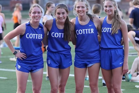 Eine Gruppe junger Athletinnen der Cotter Schools steht gemeinsam auf dem Sportfeld.