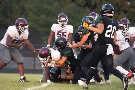 Schüler der Covenant Christian High School spielen Football auf dem Sportfeld und kämpfen um den Ball.