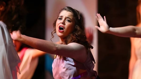 Eine Schülerin der Covenant Christian High School singt auf der Bühne vor einem bunten Hintergrund.