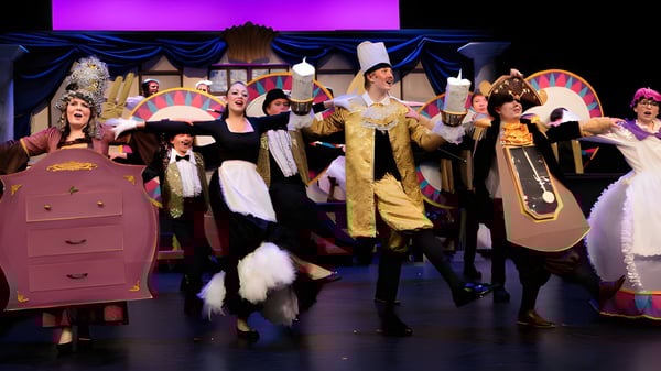 Eine Gruppe von Schülerinnen und Schülern der Covenant Christian School steht in aufwendigen Kostümen auf einer Bühne mit farbigem Theaterhintergrund.