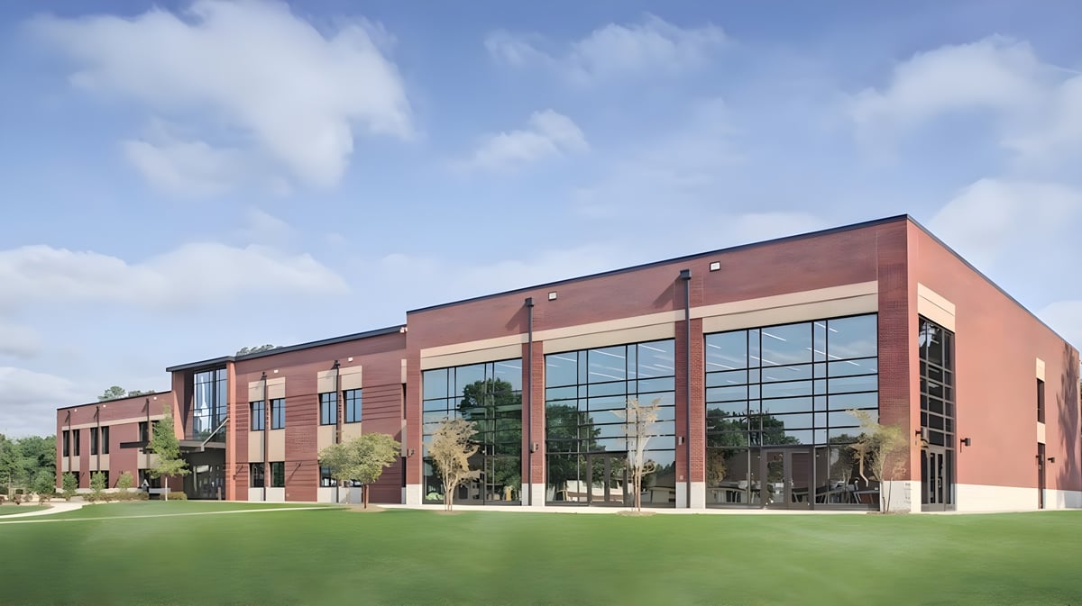 Das moderne Backsteingebäude der Covenant Day School steht auf einer Grünfläche unter blauem Himmel.