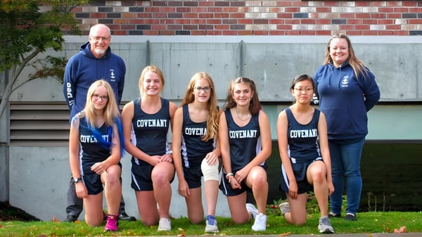 Eine Gruppe Schülerinnen der Covenant High School steht gemeinsam vor einer ziegelsteinernen Wand.