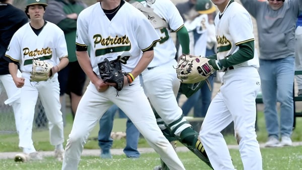 Eine Gruppe von Baseballspielern in weißen und grünen Uniformen steht auf dem Spielfeld der Coventry High School.