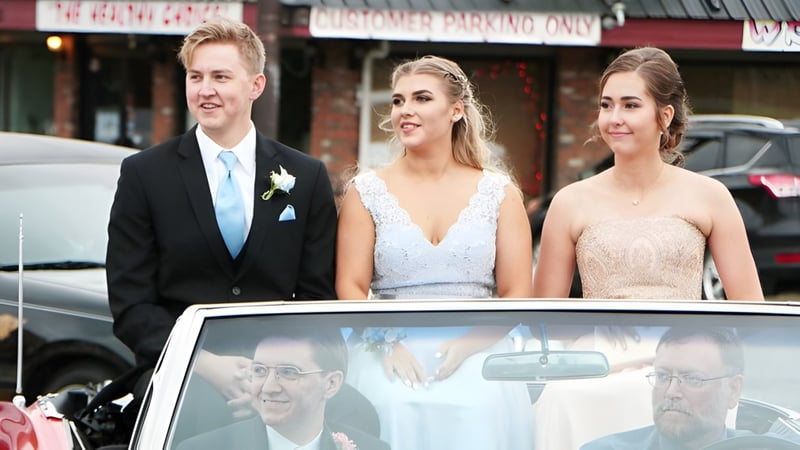 Drei Personen stehen vor einem Gebäude auf dem Gelände der Cowichan Secondary School in einem urbanen Umfeld.