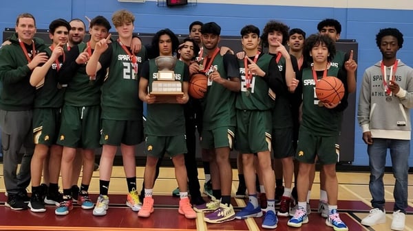 Eine Gruppe von Schülern der Craig Kielburger Secondary School posiert mit einem Basketballtrophäe in der Sporthalle.