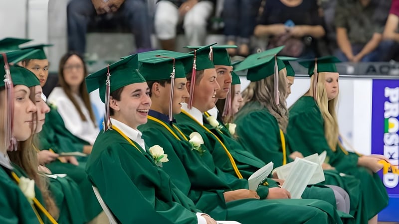 Eine Gruppe Absolventen der Craigslea State High School trägt grüne Talare und sitzt zusammen bei der Abschlussfeier.