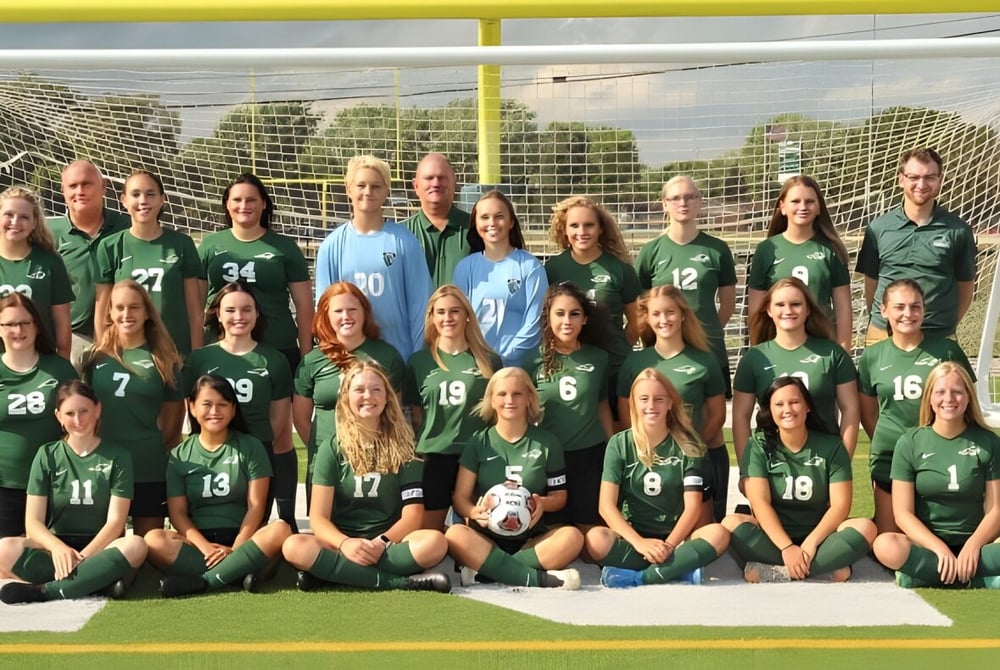 Eine Gruppe junger Fußballspielerinnen posiert auf dem Spielfeld des Cranbrook Education Campus vor dem Tor.