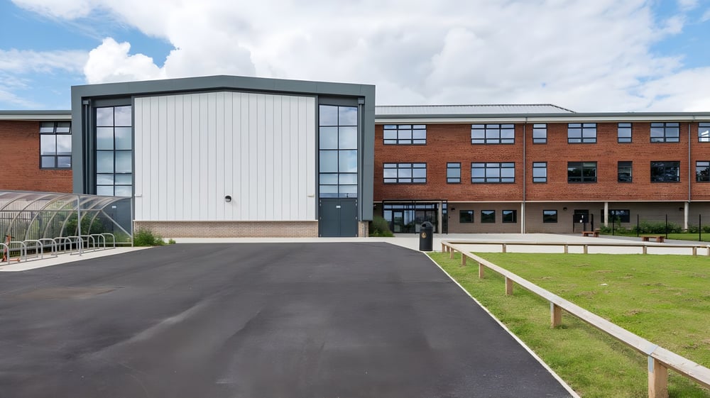 Das mehrstöckige Backsteingebäude des Cranbrook Education Campus steht umgeben von einer Rasenfläche unter blauem Himmel.