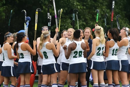 Eine Gruppe junger Tennisspielerinnen der Cranbrook Schools steht zusammen auf dem Tennisplatz mit Tennisschlägern im Hintergrund.