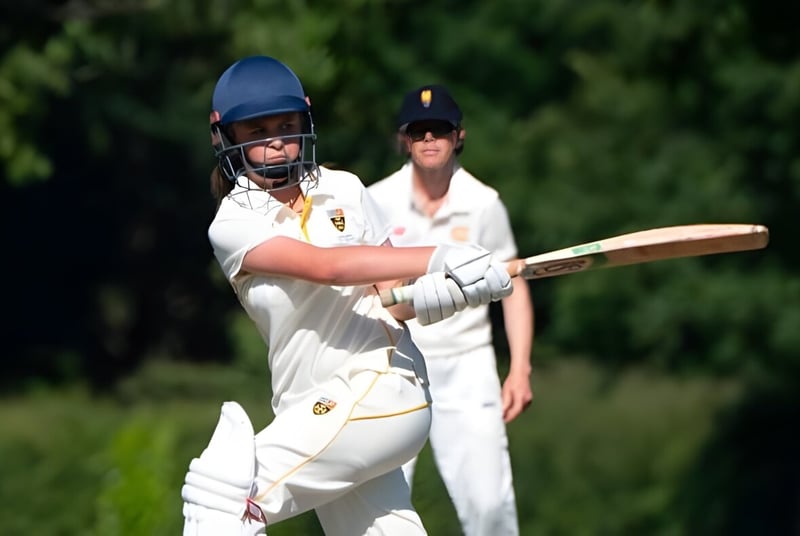 Zwei Cricket-Spieler in weißen Uniformen stehen auf dem Spielfeld der Cranleigh School.