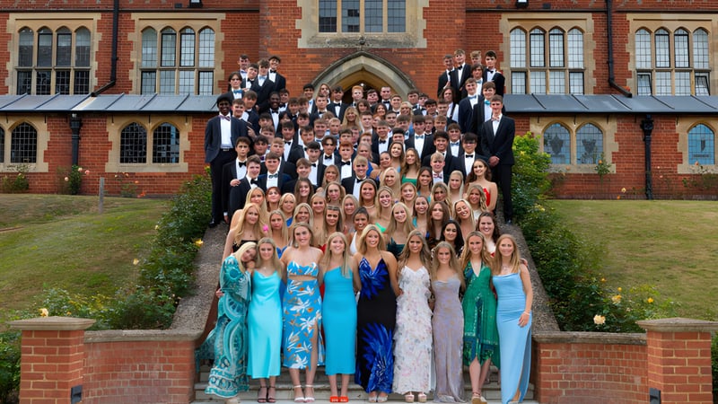 Eine Gruppe von Personen in formeller Kleidung steht vor dem historischen Gebäude der Cranleigh School.