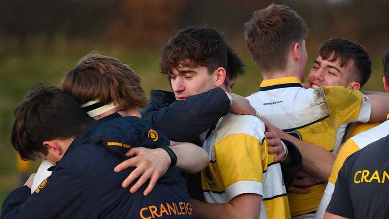 Eine Gruppe Schülerinnen und Schüler der Cranleigh School feiern gemeinsam in Sportuniformen auf dem Rasen.