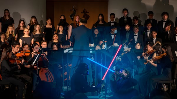 Eine Gruppe von Schülern der Crean Lutheran High School tritt auf einer Bühne mit blauer Beleuchtung auf.