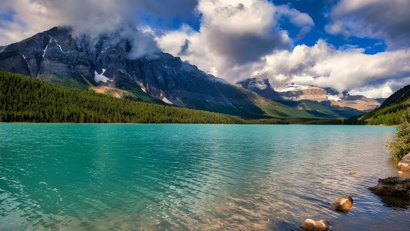 Ein ruhiger Bergsee mit schneebedeckten Gipfeln und Wäldern, umgeben von Bergen, außerhalb des Campus der Crescent Collegiate.