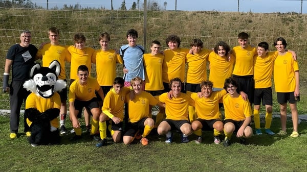 Eine Gruppe junger Fußballspielerinnen und Fußballspieler in gelben Trikots posiert auf einem Spielfeld auf dem Campus der Crescent Collegiate.