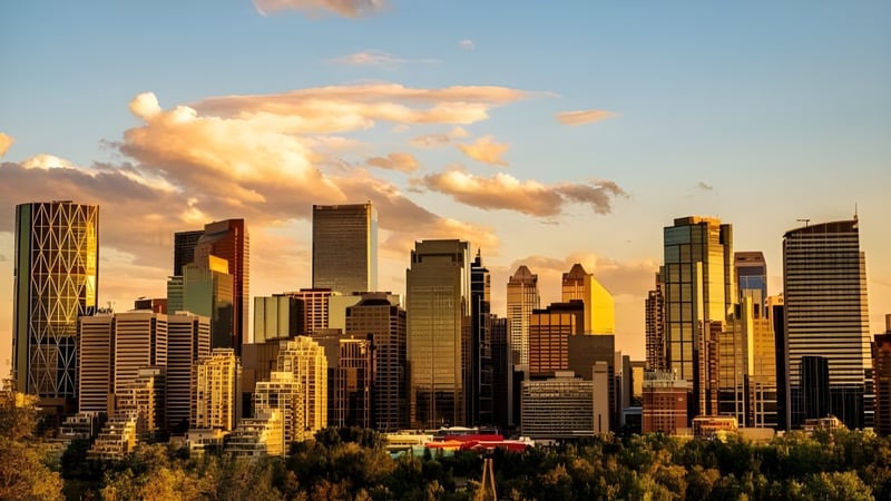 Blick auf die Skyline bei Sonnenuntergang mit grünen Flächen im Vordergrund nahe der Crescent Heights High School.