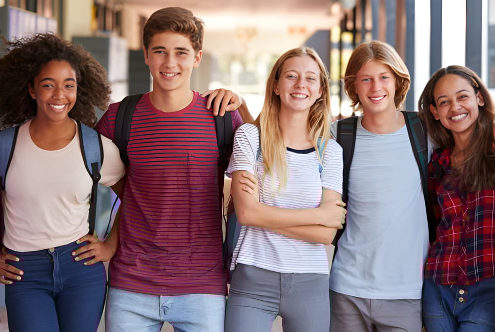 Eine Gruppe Schülerinnen und Schüler steht zusammen und lächelt auf dem Gelände der Crescent Heights High School.