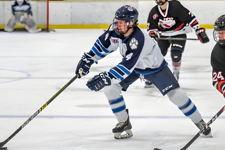 Ein Hockeyspieler der Creston Valley Secondary School trägt ein weiß-blaues Trikot und läuft auf dem Eis während eines Spiels.