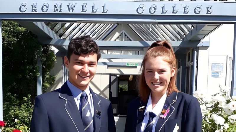 Zwei Schülerinnen und Schüler stehen vor dem Gebäude des Cromwell College.