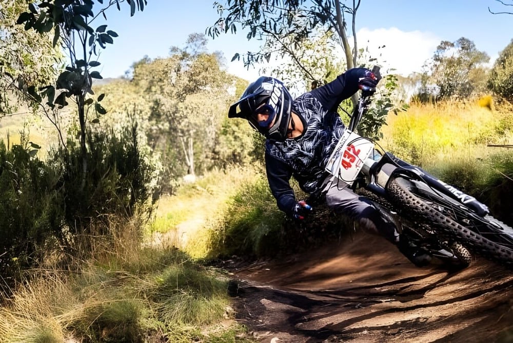 Eine Person in Tarnkleidung fährt mit einem Dirtbike auf einem kurvigen Waldweg auf dem Gelände der Cronulla High School.