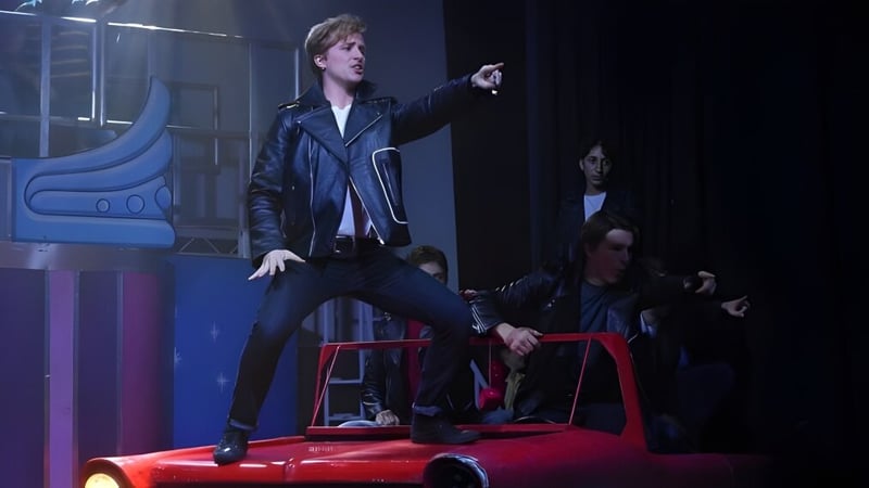 Eine Person steht auf einem roten Auto im Bühnenlicht während einer Aufführung an der Culford School.