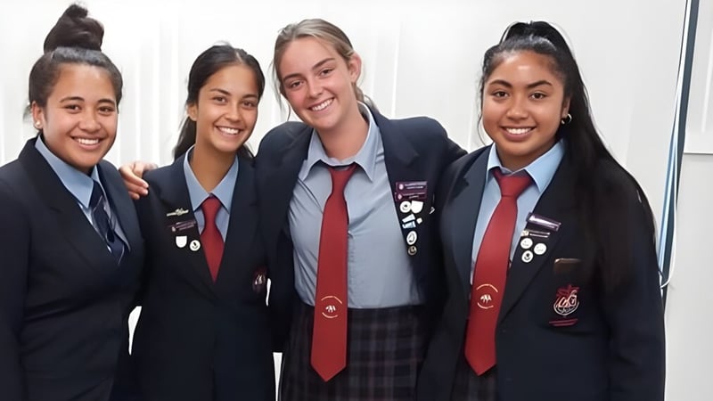 Vier Schülerinnen in Schuluniformen posieren gemeinsam in einer Klassenzimmerumgebung auf dem Campus des Cullinane College.
