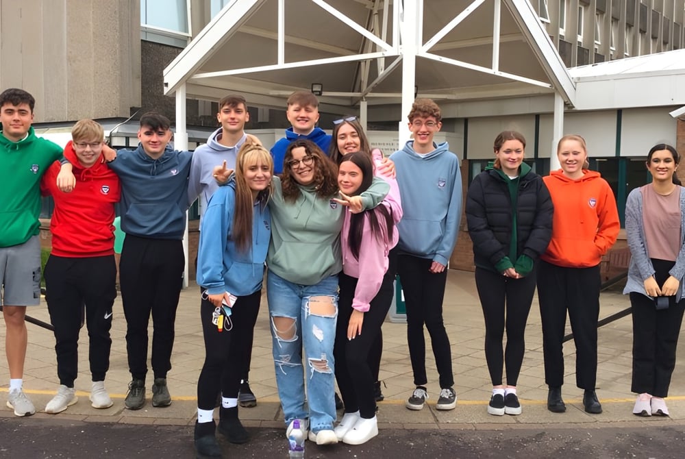 Eine Gruppe Schülerinnen und Schüler steht vor dem markanten Gebäude der Currie Community High School.