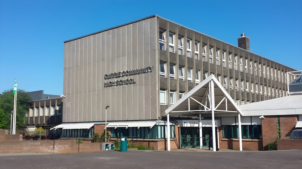 Das moderne Hauptgebäude der Currie Community High School mit angrenzendem gepflastertem Bereich und Grünflächen im Hintergrund.
