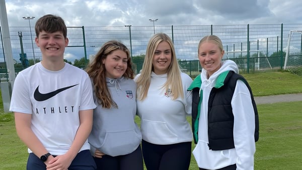 Vier Schülerinnen und Schüler stehen auf einem Sportplatzgelände der Currie Community High School.