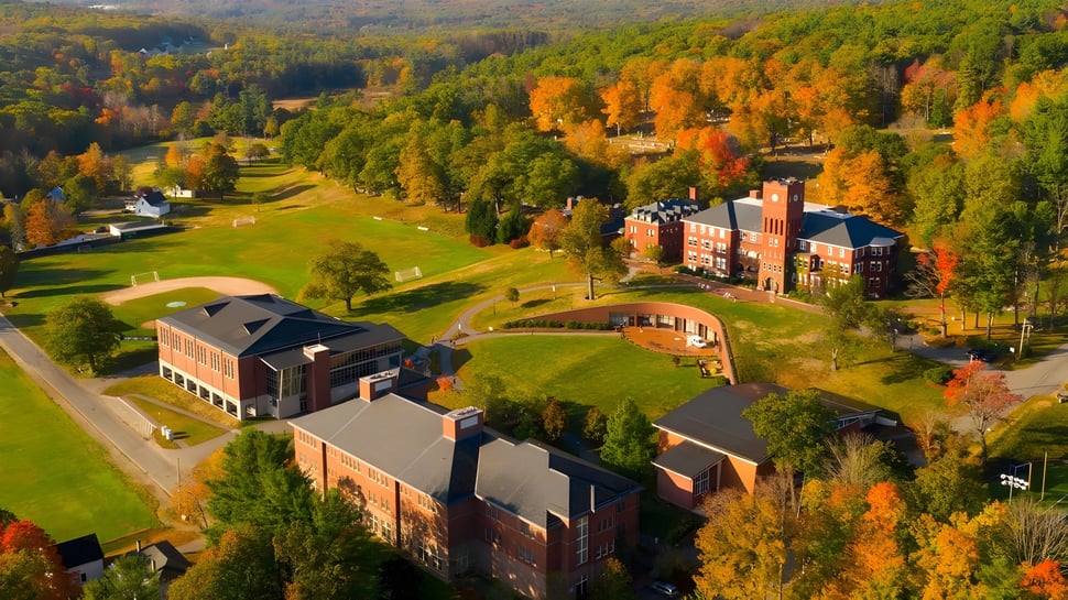 Herbstliche Landschaft mit dem Campus der Cushing Academy eingebettet in bewaldete Hügel und grüne Felder.
