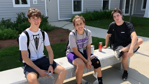 Drei Schüler sitzen auf einer Treppenstufe vor einem Gebäude auf dem Campus der Cushing Academy.