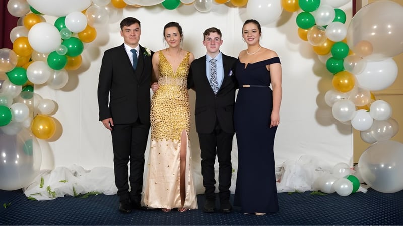 Vier Personen posieren vor bunten Luftballons und Blumen auf dem Campus der Dannevirke High School.