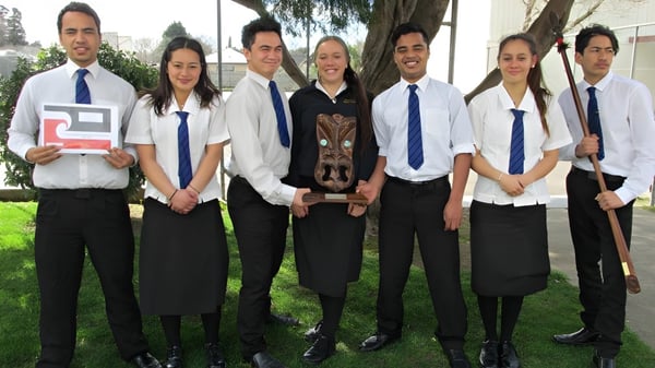 Eine Gruppe Schüler in Schuluniformen steht gemeinsam auf einer Wiese auf dem Gelände der Dannevirke High School.