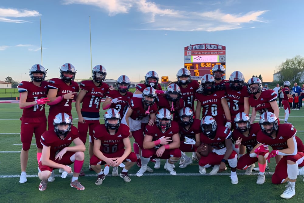 Eine Gruppe von Footballspielern in roten Trikots steht gemeinsam auf dem Sportfeld der Danville Community High School.
