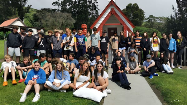 Schüler der Darfield High School versammeln sich vor einem traditionellen Maori-Meetinghaus im Grünen.