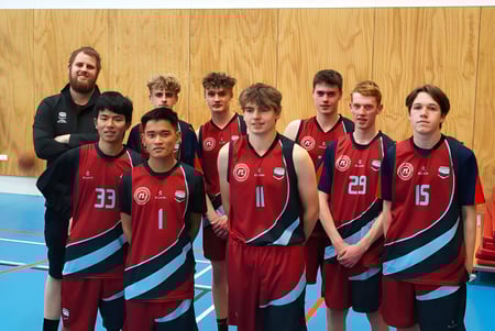 Eine Gruppe von Schülern der Darfield High School steht in Sportuniformen in einer Sporthalle vor einer Holzwand.