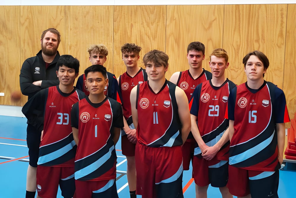 Eine Gruppe von Schülern der Darfield High School steht in Sportuniformen in einer Sporthalle vor einer Holzwand.