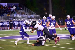 Fußballspiel mit Spielern im Tackling auf dem Spielfeld der Darlington School vor Zuschauern.