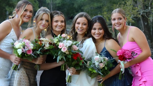 Eine Gruppe lächelnder Schülerinnen der Darlington School steht mit Blumensträußen in einem grünen Außenbereich.