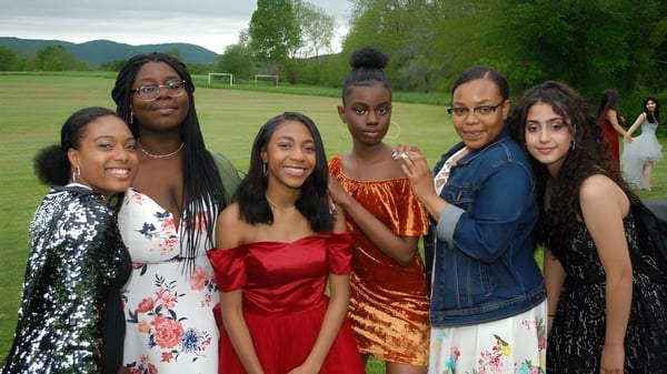 Eine Gruppe von Schülerinnen und Schülern der Darrow School steht im grünen Außenbereich mit Bergen im Hintergrund.